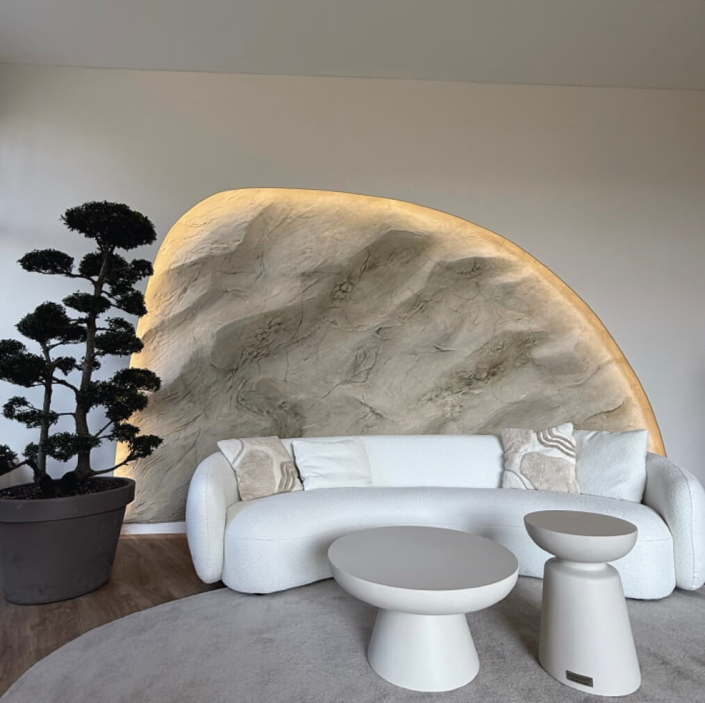 Helle Wohnlandschaft mit einem weißen Sofa, runden Tischen und einem stilvollen Baum in einem modernen Raum.