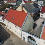 Luftaufnahme einer Wohnstraße mit roten Dächern und verschiedenen Gebäuden in einer ruhigen Wohngegend.