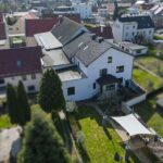 Luftaufnahme eines Wohnhauses mit Garten und Schattenplatz, umgeben von weiteren Wohngebäuden.