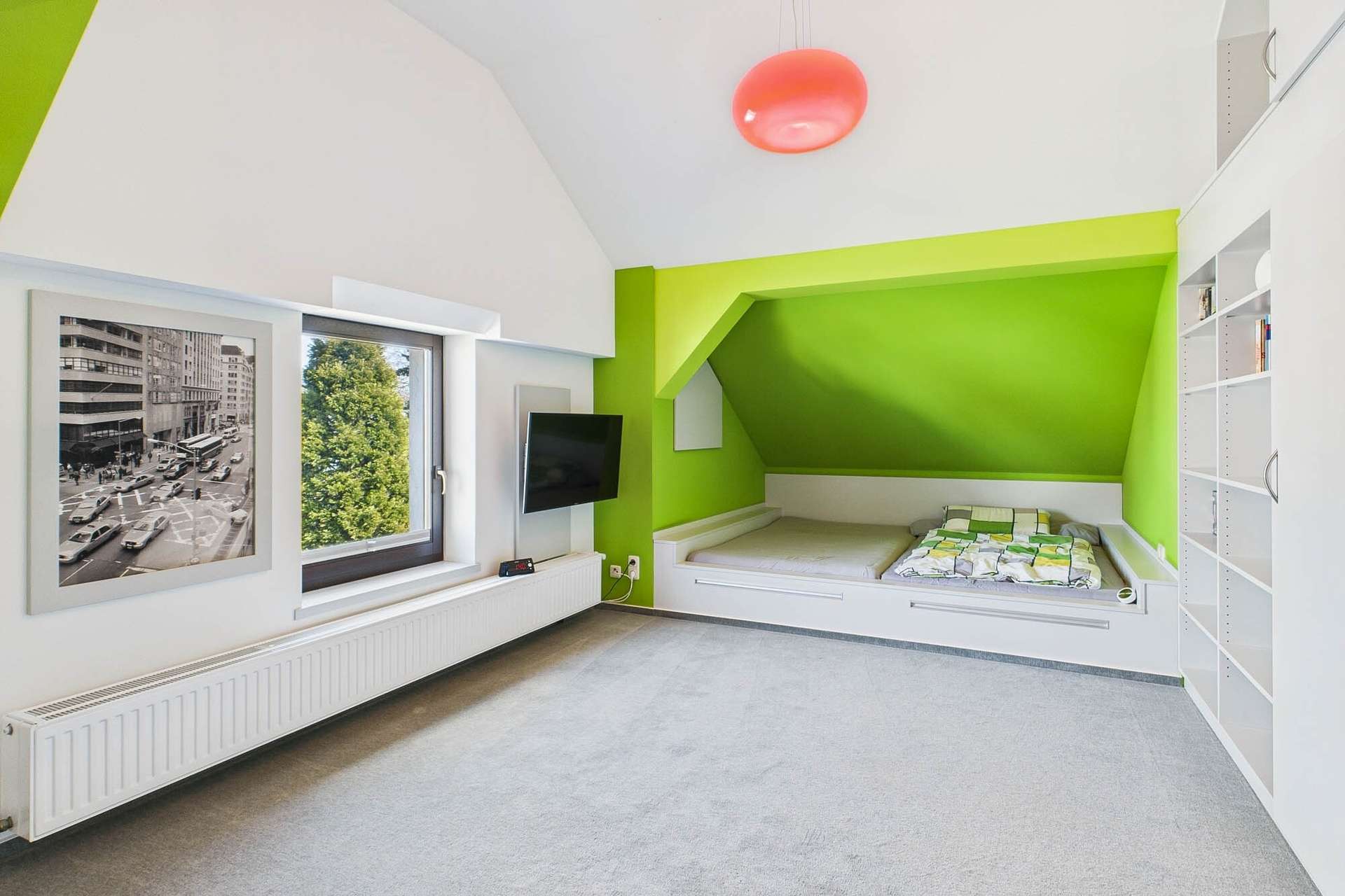 Modernes Schlafzimmer mit grünem Akzent, Fensterblick, TV und einem Bett mit Stauraum. Helle, minimalistische Einrichtung.