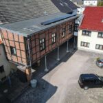 Moderne Wohnanlage mit Holz- und Ziegelarchitektur, umgeben von einem gepflasterten Parkplatz und angrenzenden Gebäuden.