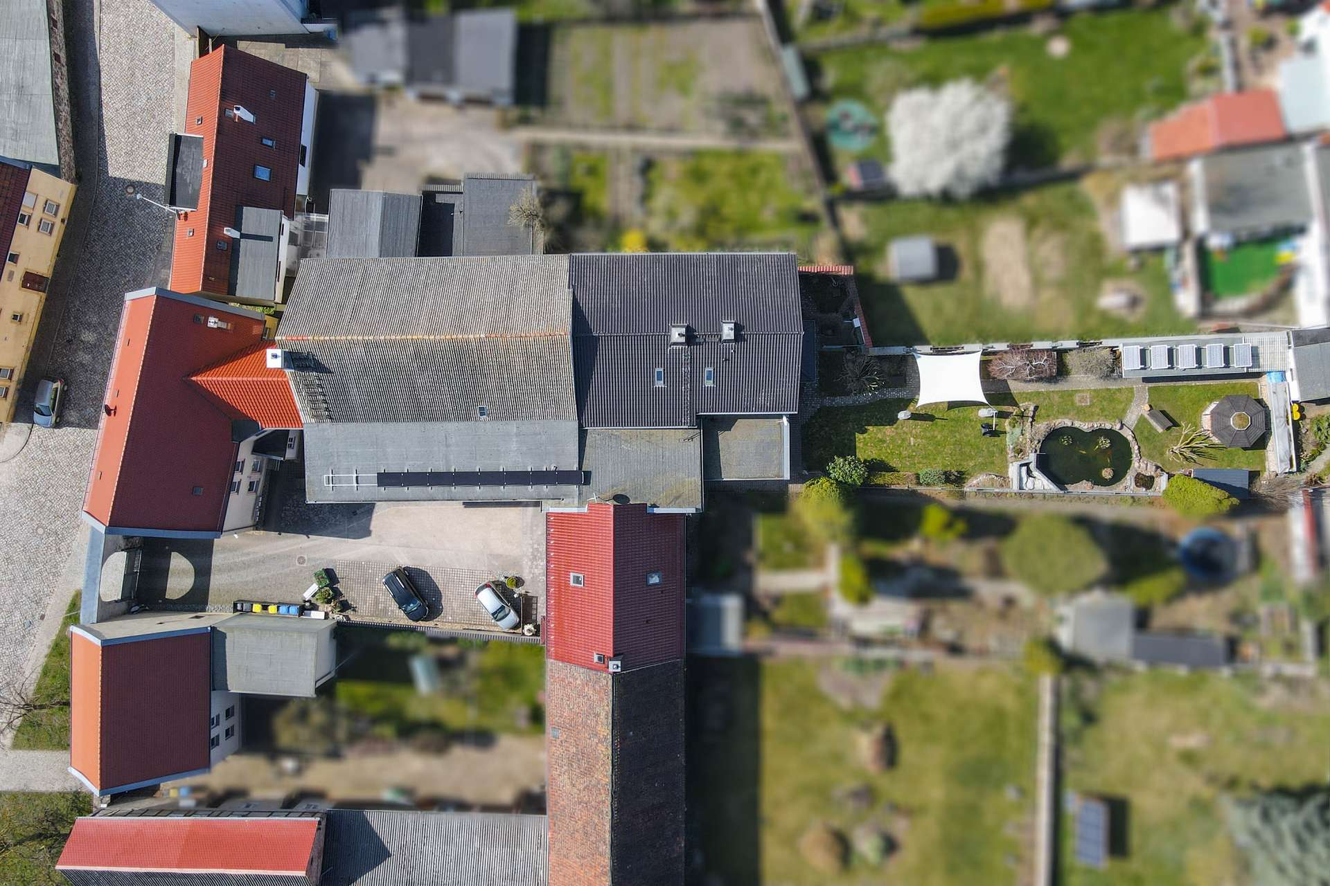 Luftaufnahme eines Wohngebiets mit mehreren Häusern, Gärten und Autos auf der Auffahrt.