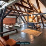 Moderne Dachgeschosswohnung mit Holzträgern, eleganten Möbeln und warmem Licht, kombiniert Industrial- und Wohnstil.
