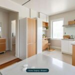 Moderne Küche mit Holz- und weißen Möbeln, hellem Licht und Pflanzen, die eine einladende Atmosphäre schaffen.