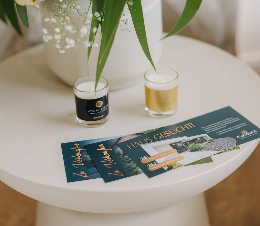 Zwei Kerzen und ein Flyer auf einem Tisch, der eine Immobilienanzeige mit dem Titel
