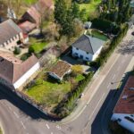 Luftaufnahme eines Wohngebiets mit Einfamilienhäusern, Gärten und einer ruhigen Straße.