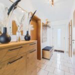 Moderne Eingangshalle mit einer Kommode, Spiegel, dekorativen Vasen und Holzaccessoires. Helle, freundliche Atmosphäre.