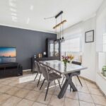 Moderne Esszimmeransicht mit grauem Tisch, Stühlen, TV und eleganten Dekorationen an der Wand.