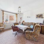 Gemütliches Wohnzimmer mit einem Sofa, einem Tisch und Fenstern, die Tageslicht hereinlassen. Vintage-Dekor und Möbel.