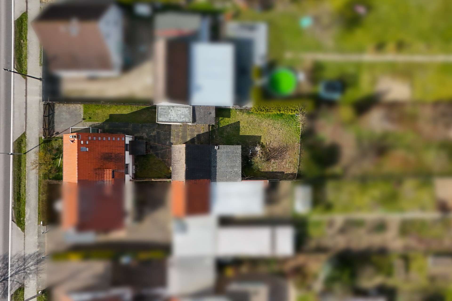 Vogelperspektive auf ein Wohngebiet mit Gärten und Wohnhäusern, im Fokus ein Haus mit roten Ziegeln.