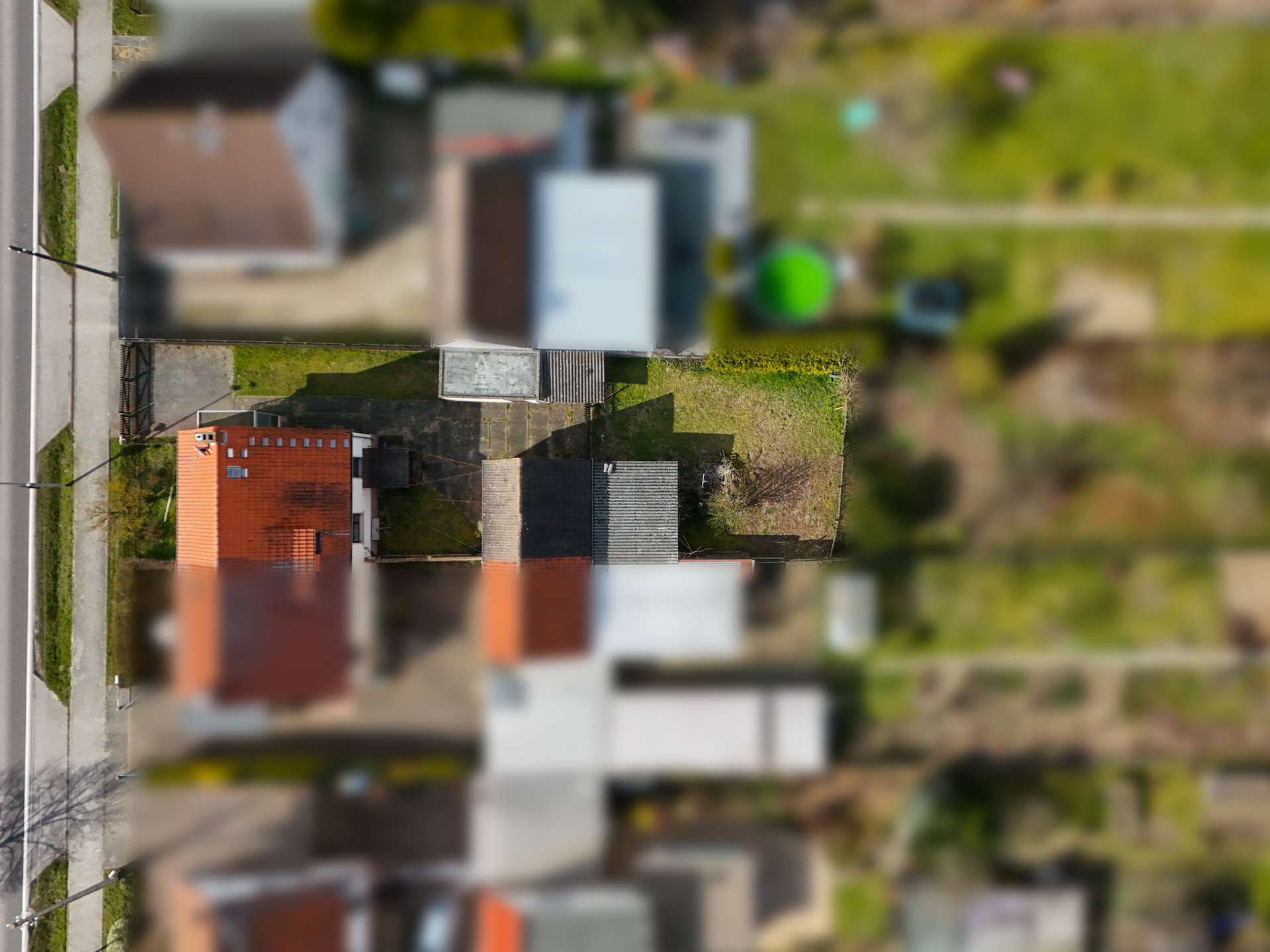 Vogelperspektive auf ein Wohngebiet mit Gärten und Wohnhäusern, im Fokus ein Haus mit roten Ziegeln.