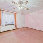 Leerer Raum mit pinken Wänden, einem Fenster mit Vorhängen und einem Deckenventilator.
