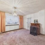 Helles Wohnzimmer mit Teppich, Kamin, eleganten Vorhängen und einem Kronleuchter an der Decke.