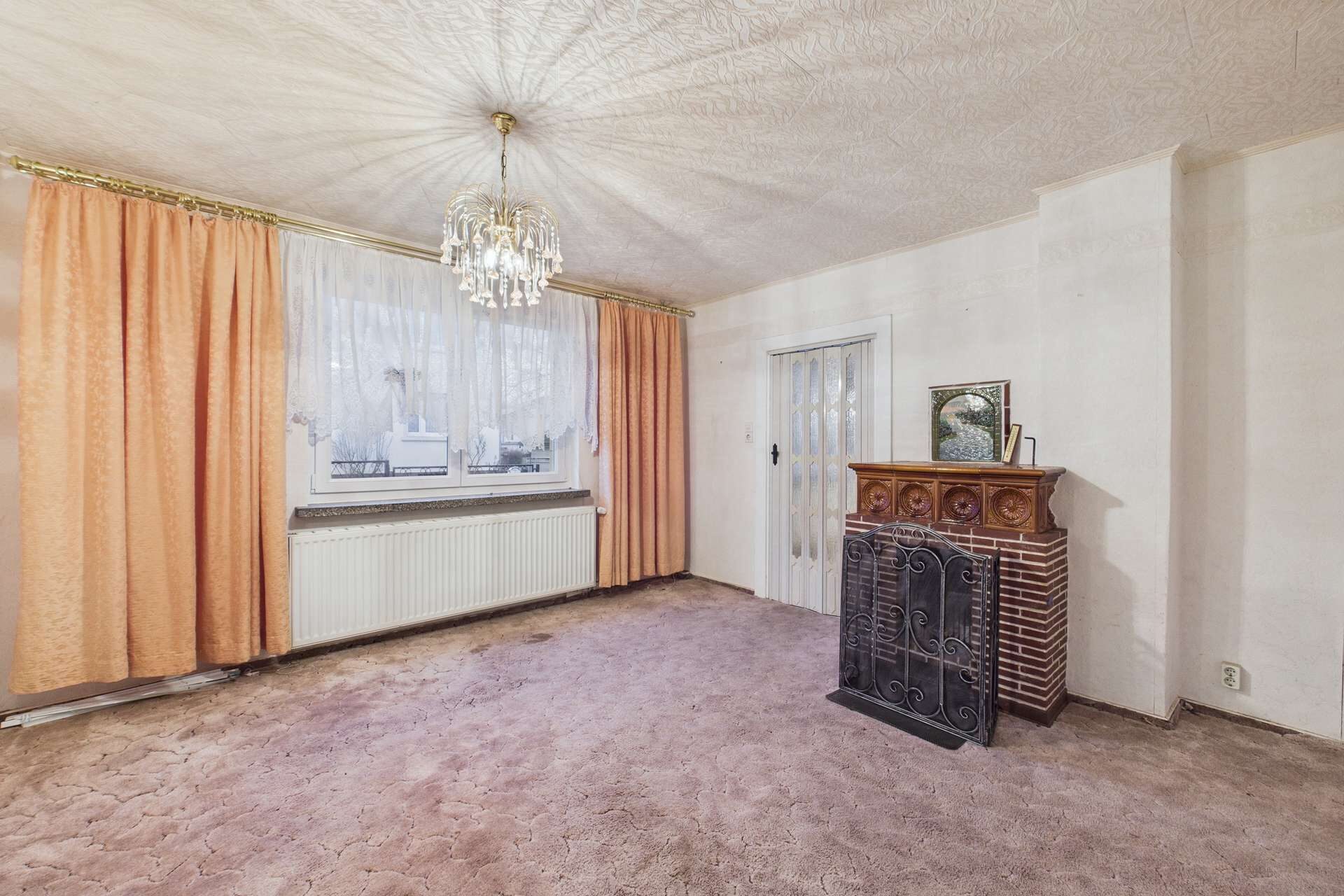 Helles Wohnzimmer mit Teppich, Kamin, eleganten Vorhängen und einem Kronleuchter an der Decke.