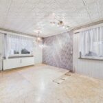 Leerer Raum mit hellen Wänden, Fenster mit Vorhängen und einem gemusterten Akzentwand.