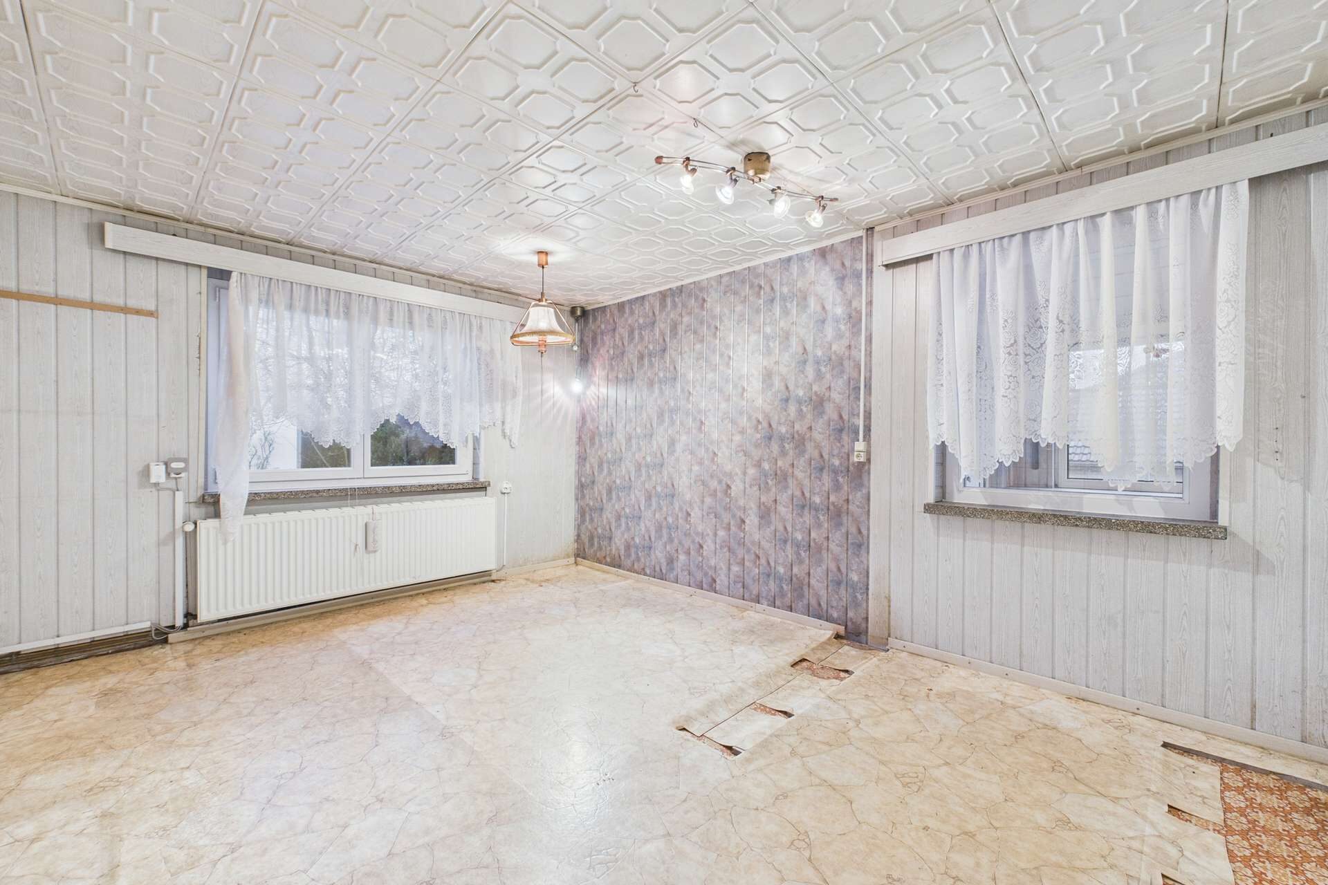 Leerer Raum mit hellen Wänden, Fenster mit Vorhängen und einem gemusterten Akzentwand.