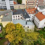 Luftaufnahme von Wohngebäuden mit herbstlichen Bäumen in einer städtischen Umgebung.