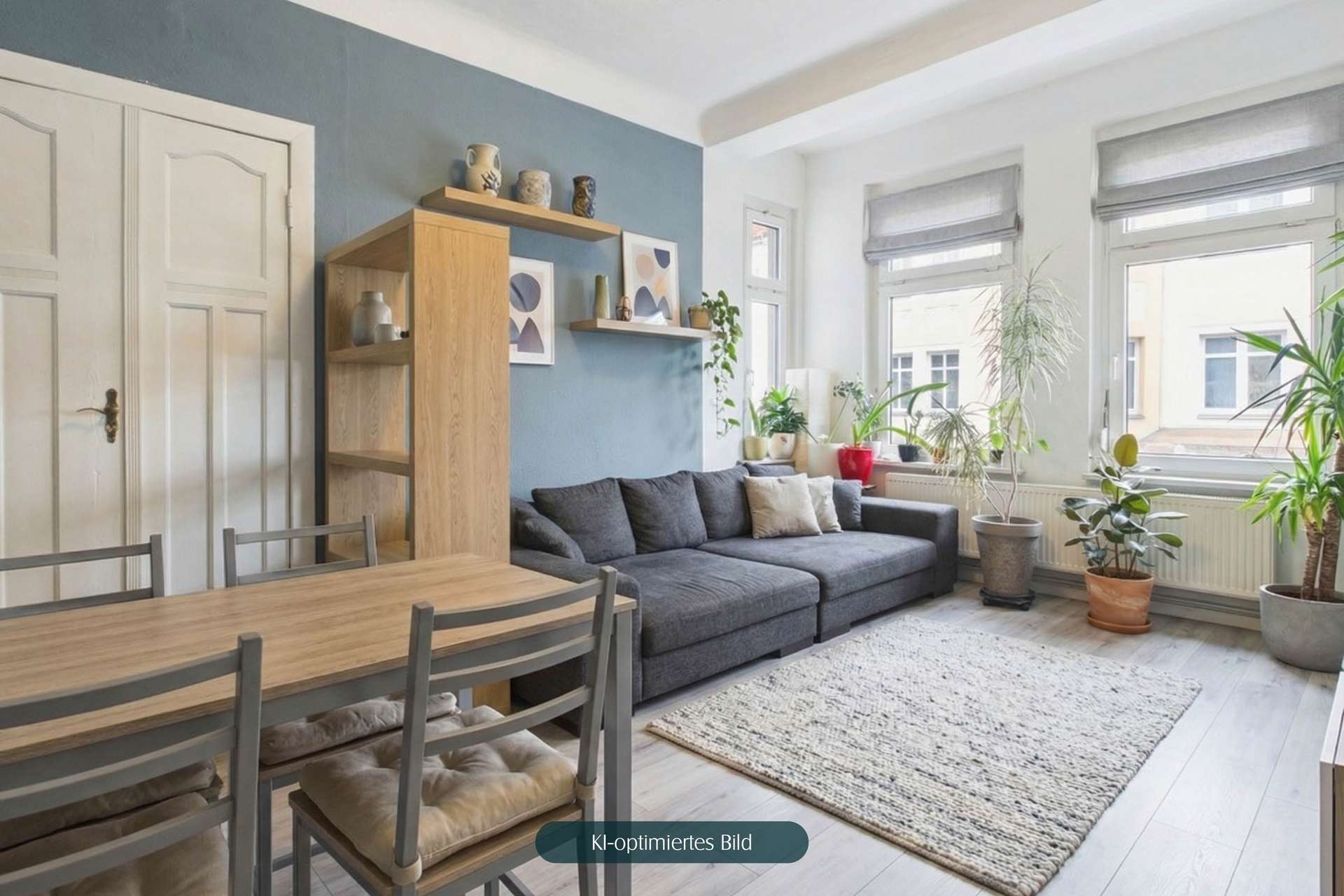 Heller Wohnraum mit grauem Sofa, Esstisch und Pflanzen, dekoriert mit modernen Kunstwerken und Vasen.