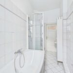 Badezimmer mit Dusche, Badewanne und weißen Fliesen, helle und moderne Gestaltung.