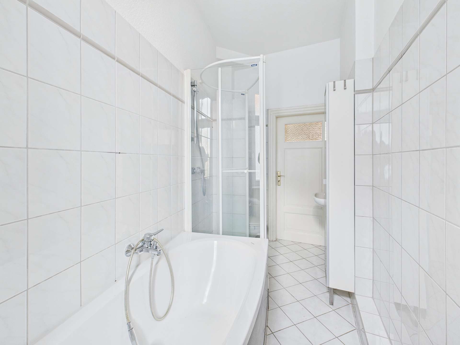 Badezimmer mit Dusche, Badewanne und weißen Fliesen, helle und moderne Gestaltung.