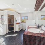 Helles Badezimmer mit Doppelwaschbecken, Sauna und großen Fenstern, modernen Fliesen und eleganten Details.