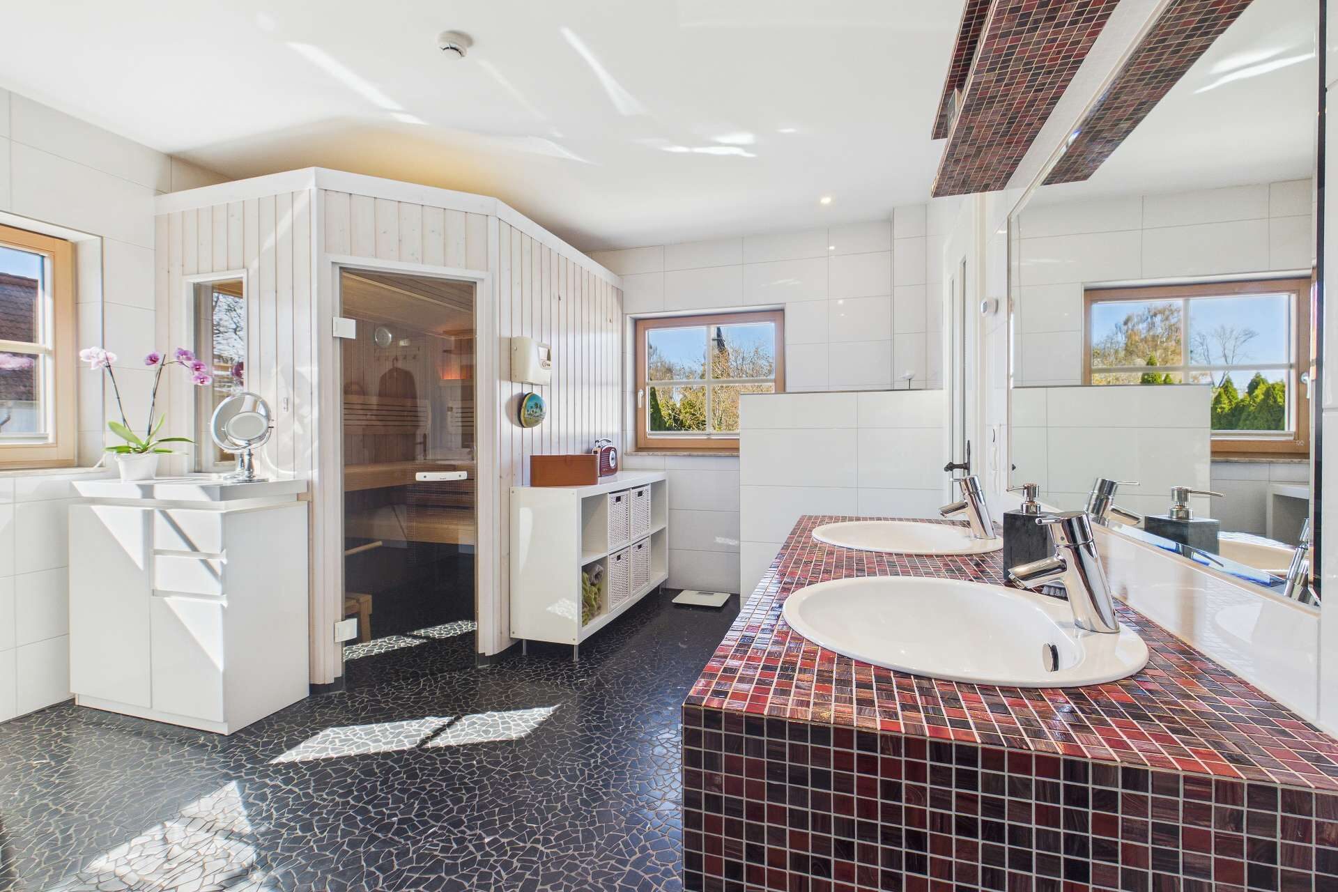 Helles Badezimmer mit Doppelwaschbecken, Sauna und großen Fenstern, modernen Fliesen und eleganten Details.