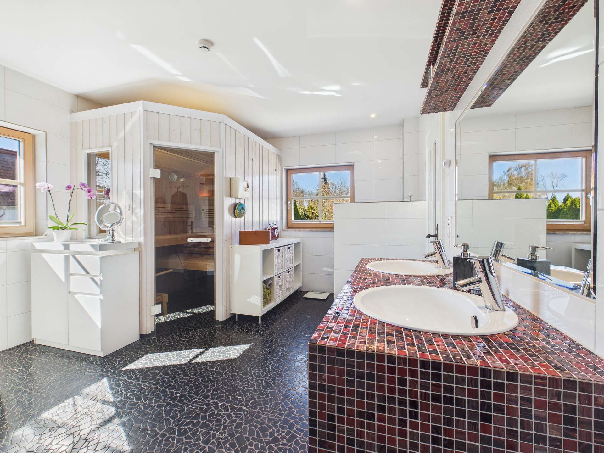 Helles Badezimmer mit Doppelwaschbecken, Sauna und großen Fenstern, modernen Fliesen und eleganten Details.
