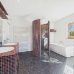 Modernes Badezimmer mit Dusche, Badewanne, Doppelwaschtisch und eleganten Fliesen im schwarz-roten Design.