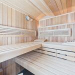 Innenansicht einer Holzsauna mit Bänken, Holzverkleidung und einer Wanduhr.