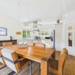 Moderne Küche mit Essbereich, Holzstisch und eleganten Stühlen in einem hellen, offenen Raum.