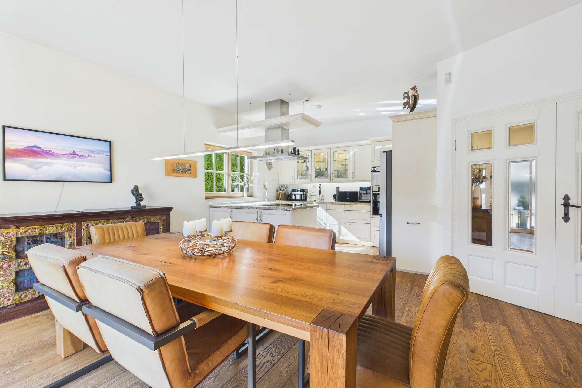 Moderne Küche mit Essbereich, Holzstisch und eleganten Stühlen in einem hellen, offenen Raum.
