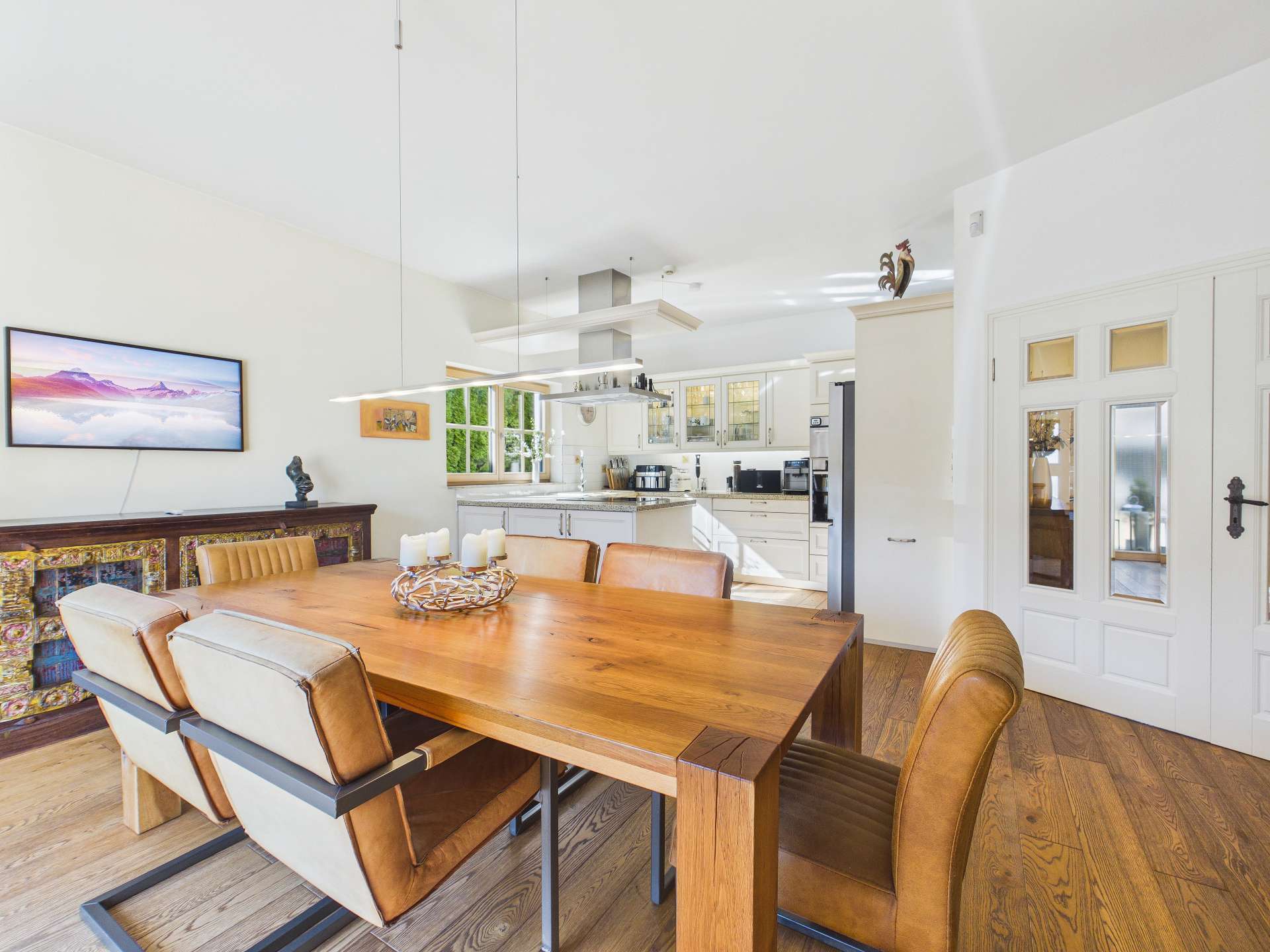 Moderne Küche mit Essbereich, Holzstisch und eleganten Stühlen in einem hellen, offenen Raum.
