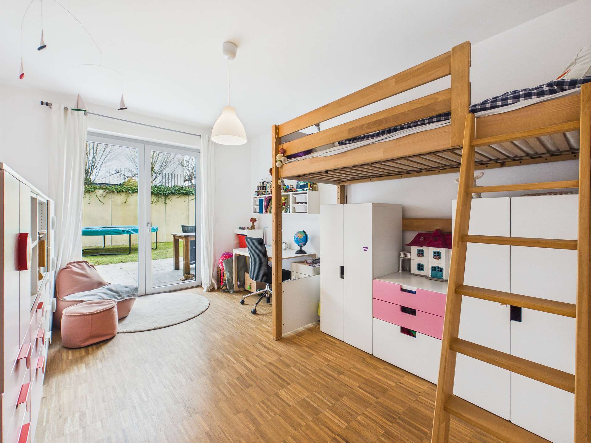 Kinderzimmer mit Hochbett, Schreibtisch, Stauraum und Zugang zu einem Garten durch große Fenster.