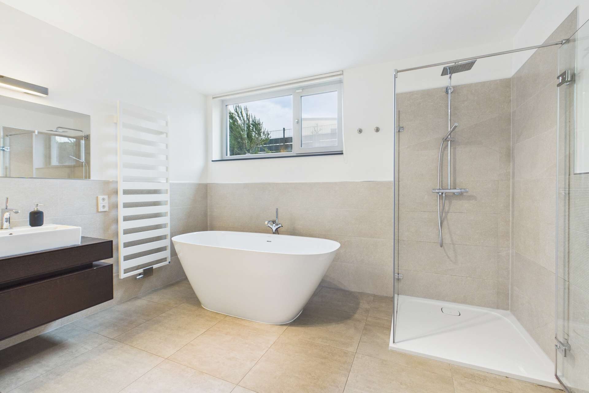 Modernes Badezimmer mit freistehender Badewanne, Dusche, großem Fenster und eleganten Fliesen.