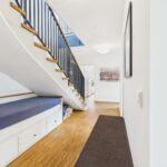 Blick auf einen modernen Flur mit Treppe, Sitzbank und hellem Holzfußboden.
