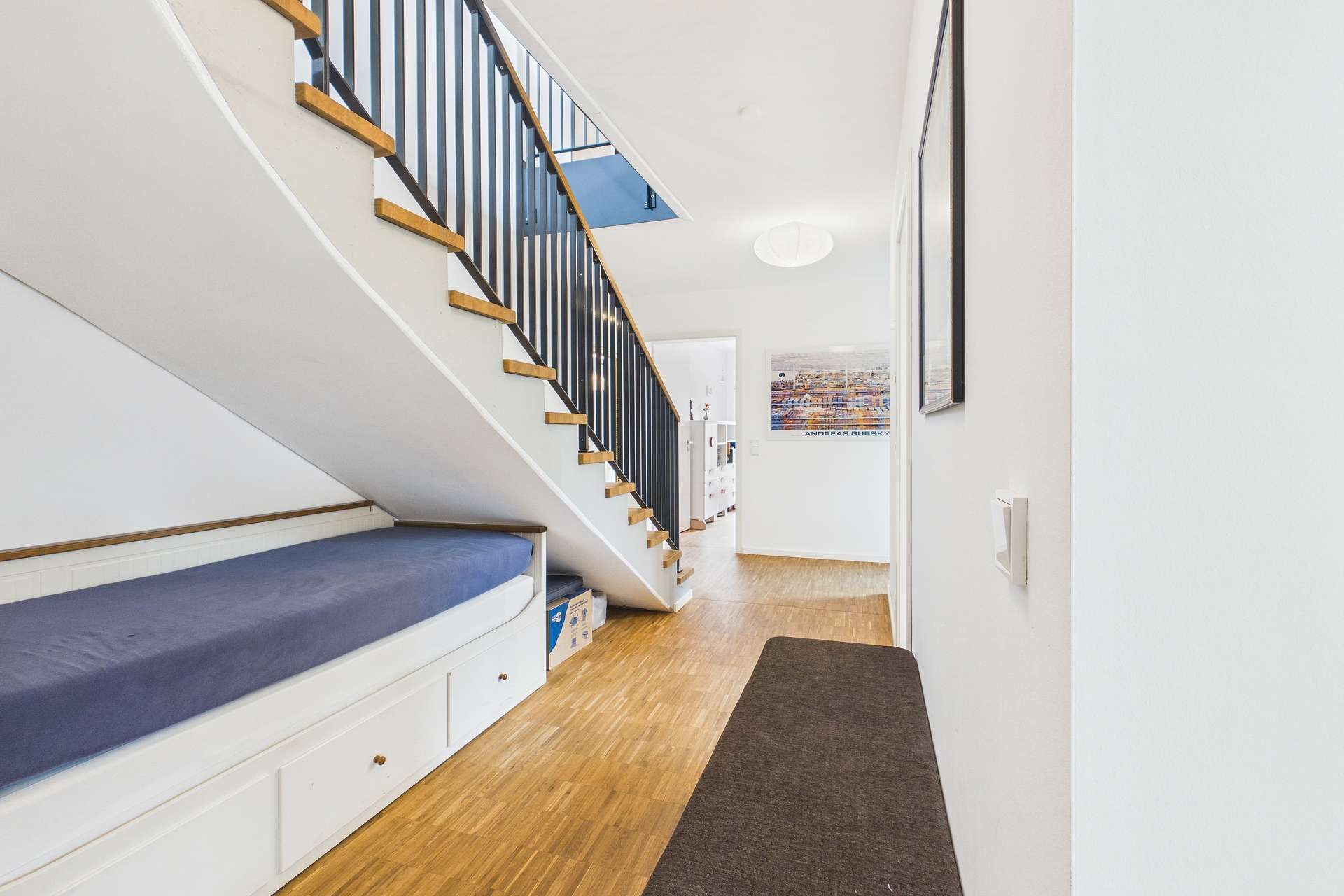 Blick auf einen modernen Flur mit Treppe, Sitzbank und hellem Holzfußboden.
