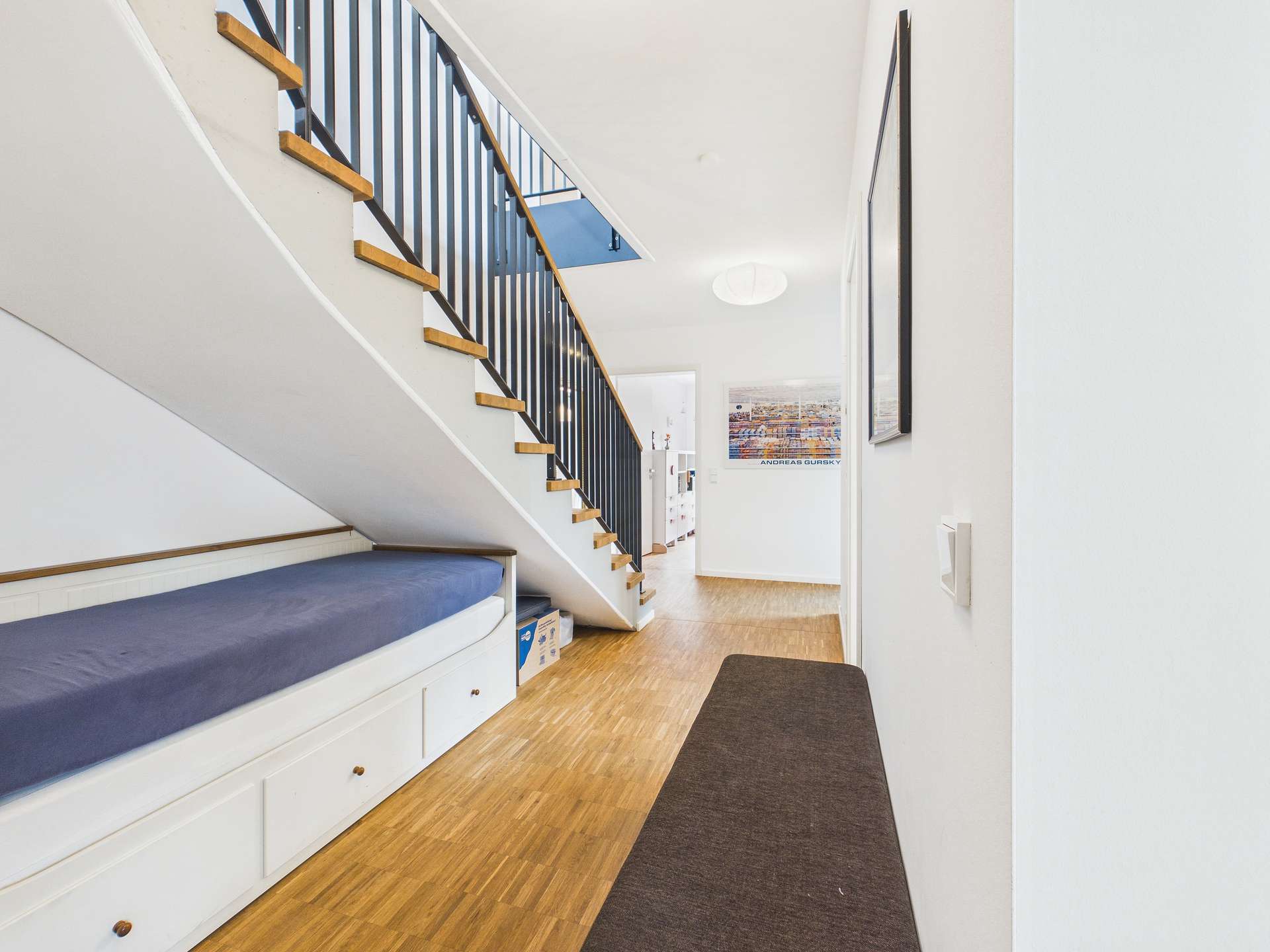 Blick auf einen modernen Flur mit Treppe, Sitzbank und hellem Holzfußboden.