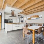 Moderne Küche mit Holzdecke, eleganter Esstisch und Stühlen in einem offenen Raum.