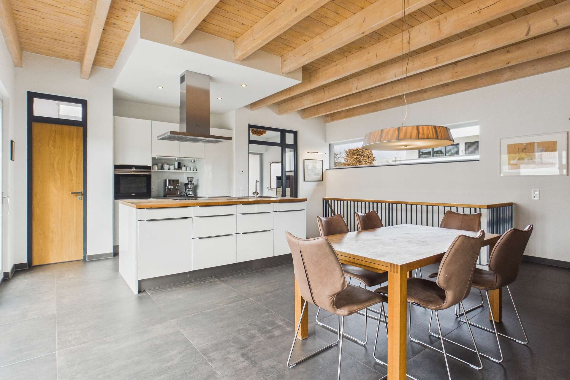 Moderne Küche mit Holzdecke, eleganter Esstisch und Stühlen in einem offenen Raum.