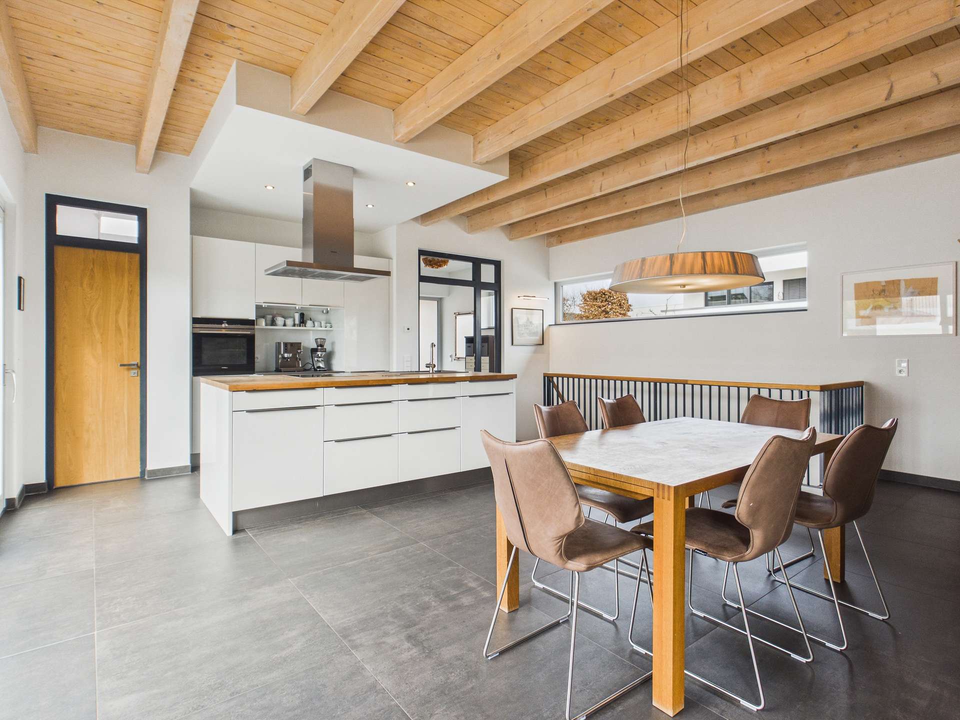Moderne Küche mit Holzdecke, eleganter Esstisch und Stühlen in einem offenen Raum.
