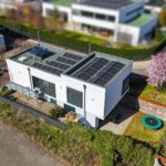 Ein modernes Haus mit Solarpanelen, umgeben von Grünflächen und einem Trampolin im Garten.