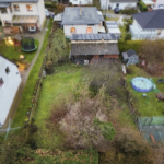 Luftaufnahme eines Gartens mit einem Wohnhaus, umgeben von Bäumen und Hecken, in einer Wohngegend.