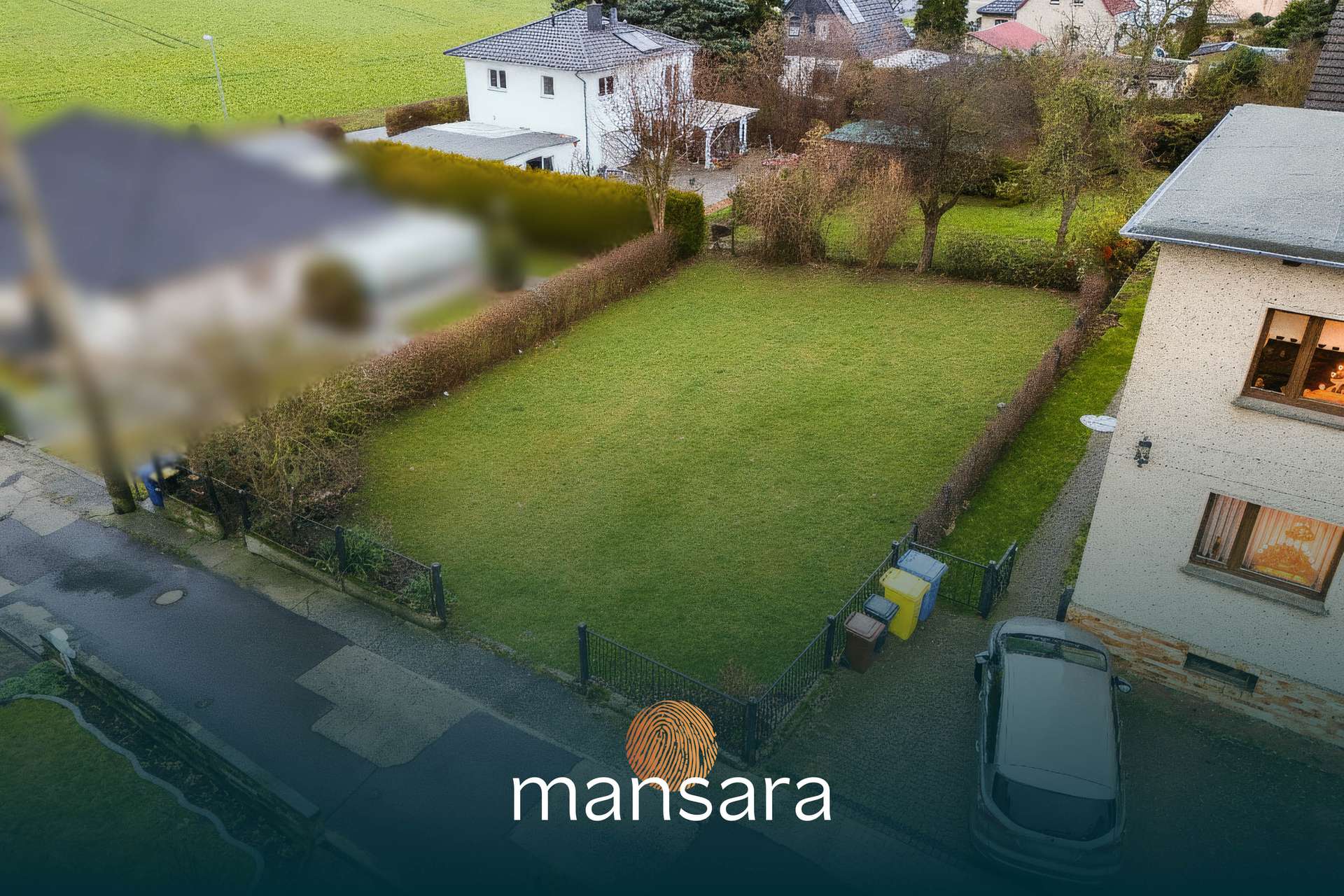 Luftaufnahme eines unbebauten Grundstücks mit gepflegtem Rasen, umgeben von Hecken und benachbarten Häusern.