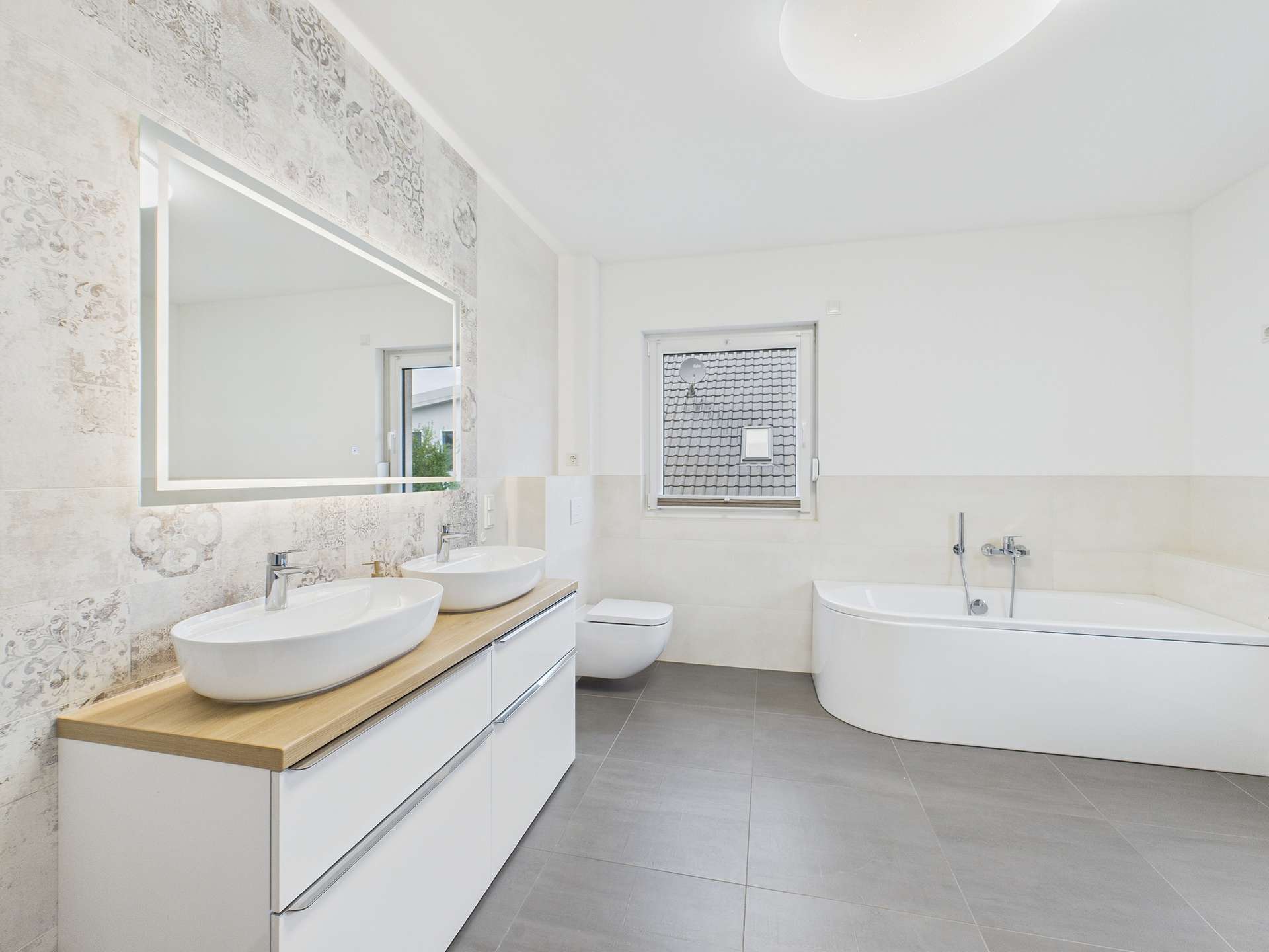 Modernes Badezimmer mit Doppelwaschbecken, freistehender Badewanne und großem Spiegel. Helle, neutrale Farbtöne.