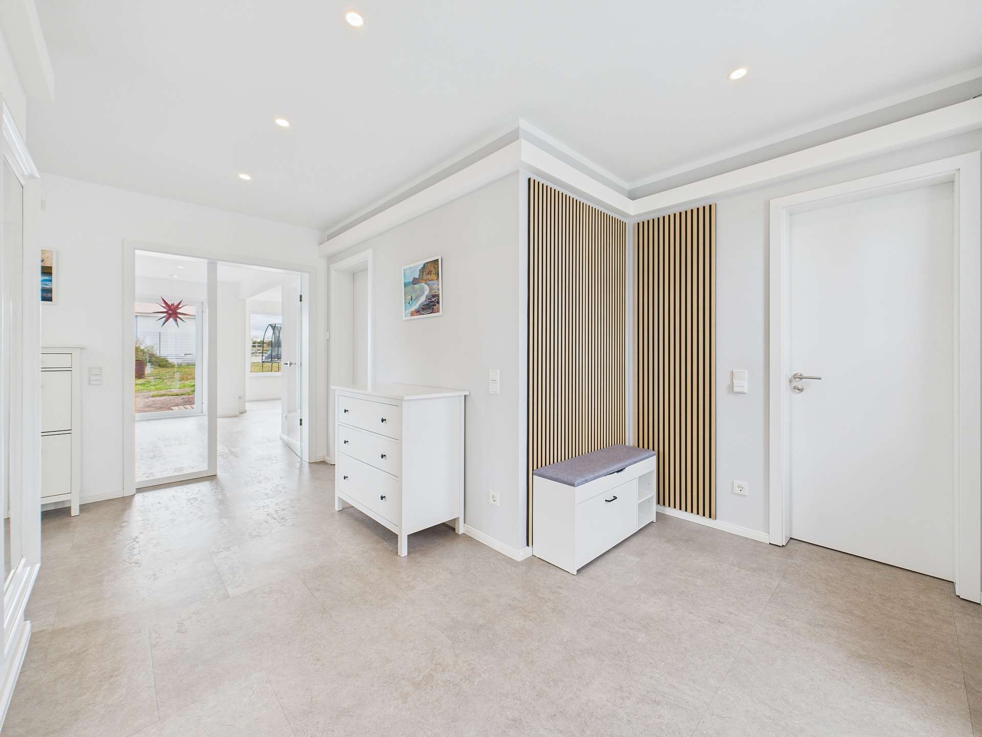 Heller Flur mit weißen Möbeln, einer Kommode und einer Sitzbank mit Holzpaneelen an der Wand.