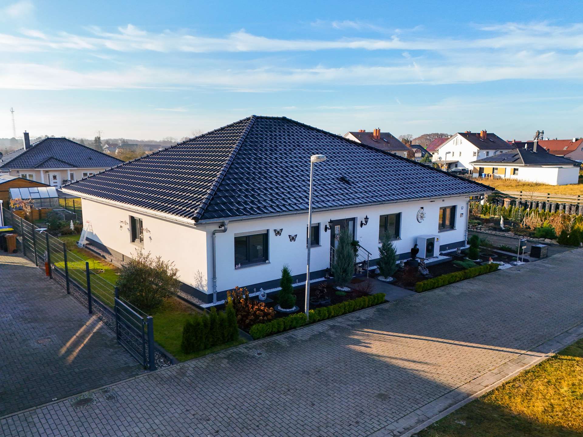 Ein modernes Einfamilienhaus mit Satteldach, umgeben von einem gepflegten Garten und einer gepflasterten Einfahrt.