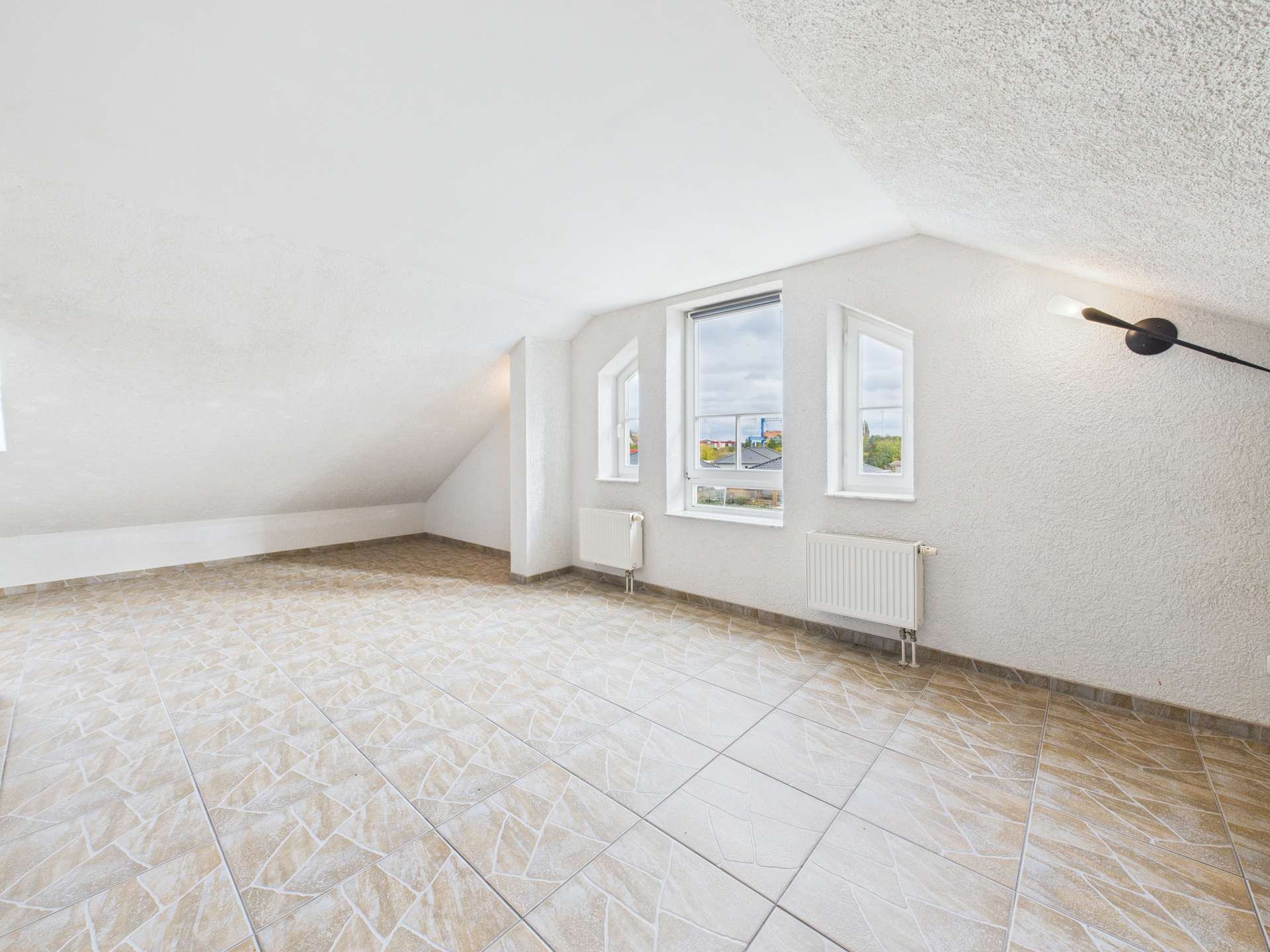 Helle Dachgeschosswohnung mit weißen Wänden, großen Fenstern und modernen Fliesenböden.