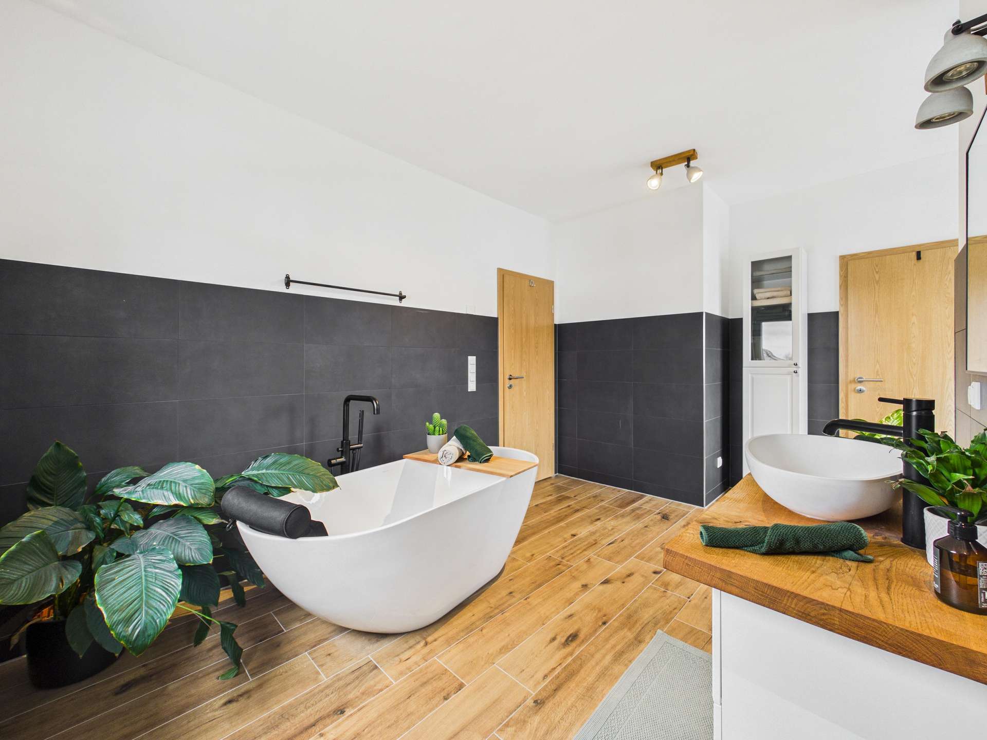 Modernes Badezimmer mit freistehender Badewanne, Pflanzen und Holzregal in neutralen Farben.