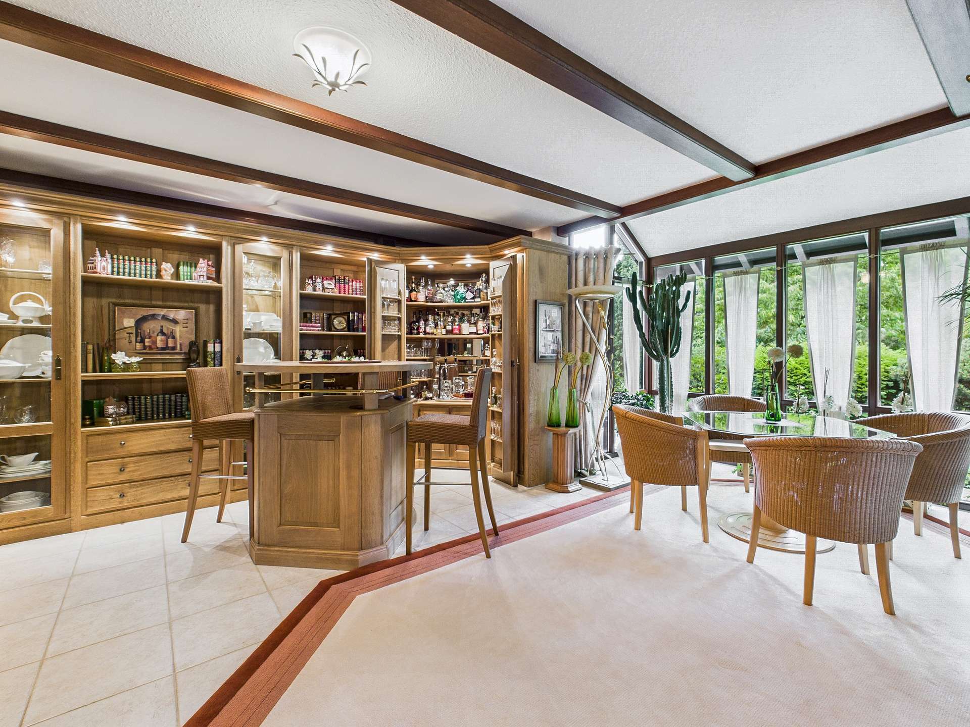 Eleganter Wohnbereich mit Bar, Holzregalen und großzügigen Fenstern, die Blick auf den Garten bieten.