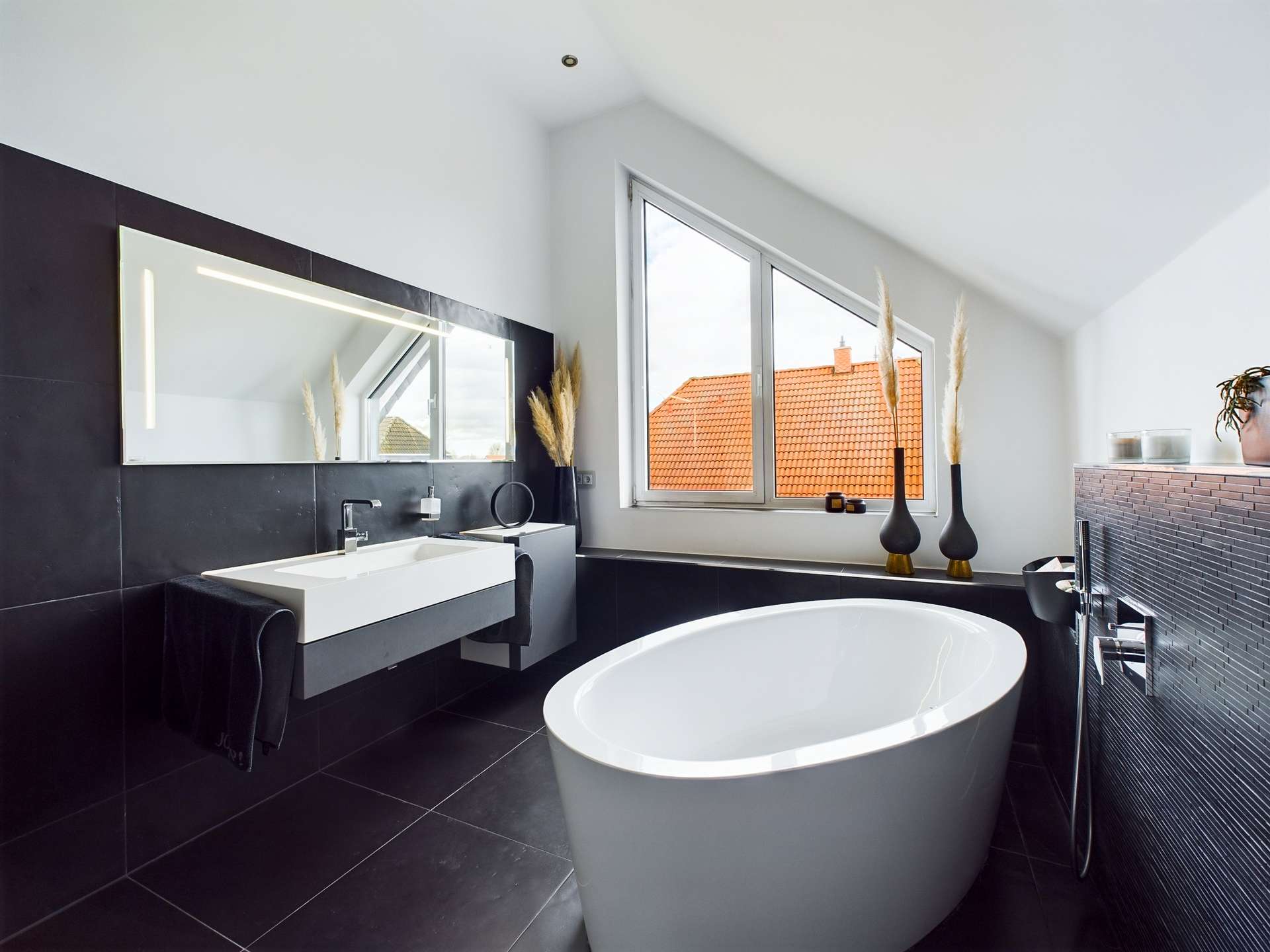 Modernes Badezimmer mit freistehender Badewanne, großem Spiegel und Fenstern, die Tageslicht hereinlassen.